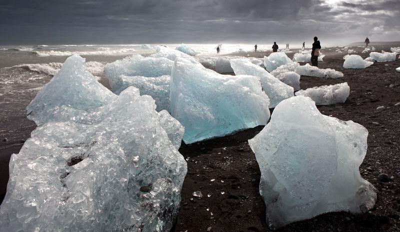 Tourist on black sand beach, Icebergs from the Jokulsarlon Glacial Lagoon on Breioamerkurfjara beach, Eastern Iceland